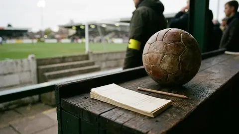 Alter Holztresen mit leeren Wettscheinen, einem Bleistift und einem abgenutzten Lederfußball im warmen Licht