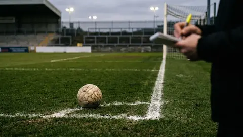 Fußball auf dem Elfmeterpunkt eines leeren Spielfelds unter abendlichem Flutlicht